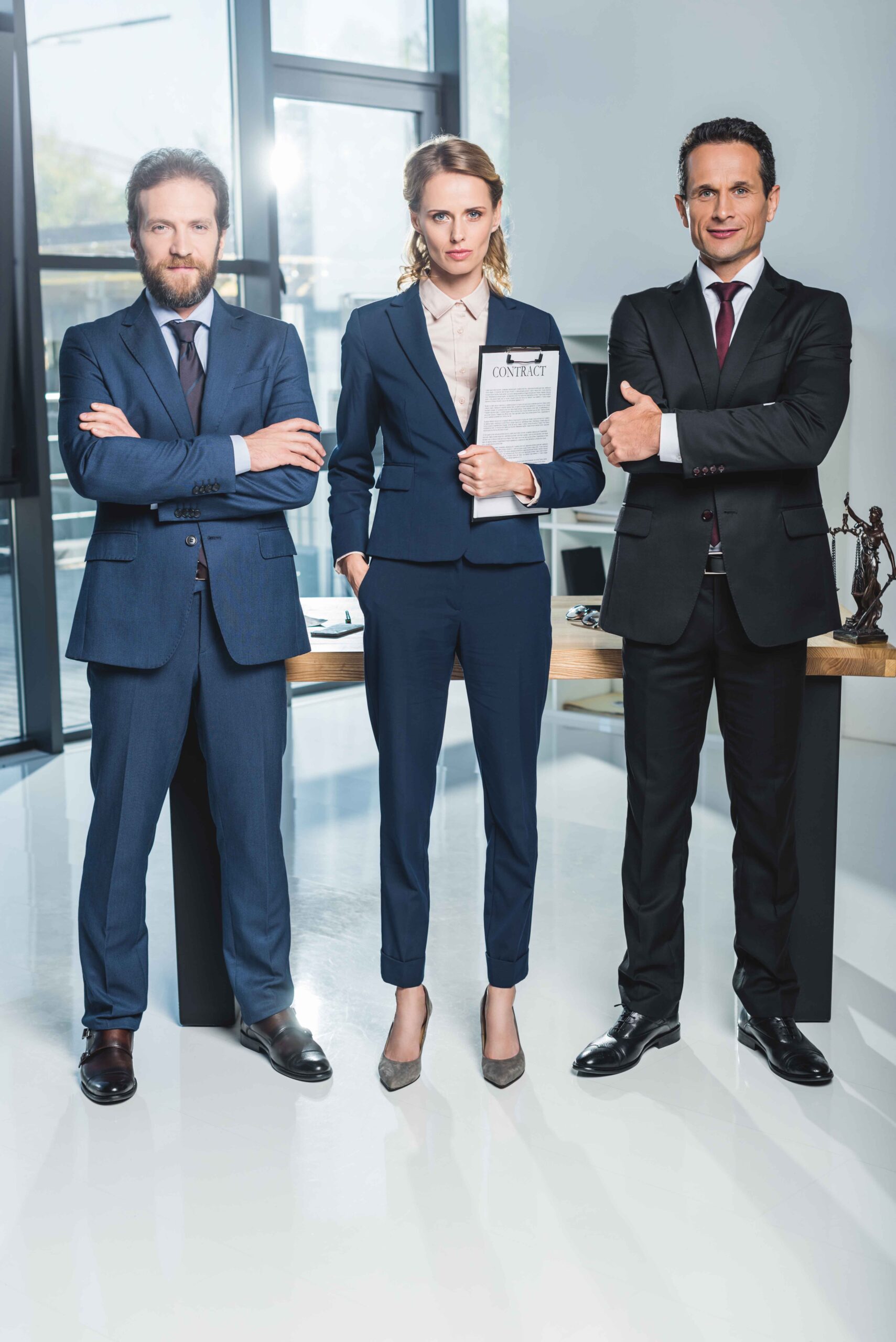 lawyers with arms crossed standing near colleague that holding c